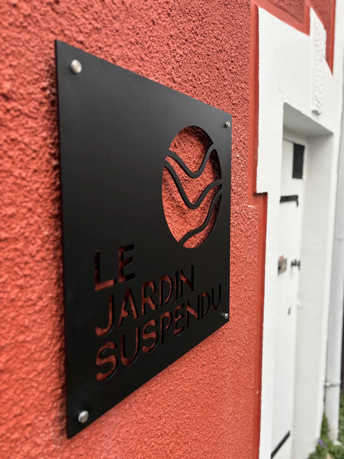 Plaque découpée sur mesure avec logo et texte évidés, posée sur une façade